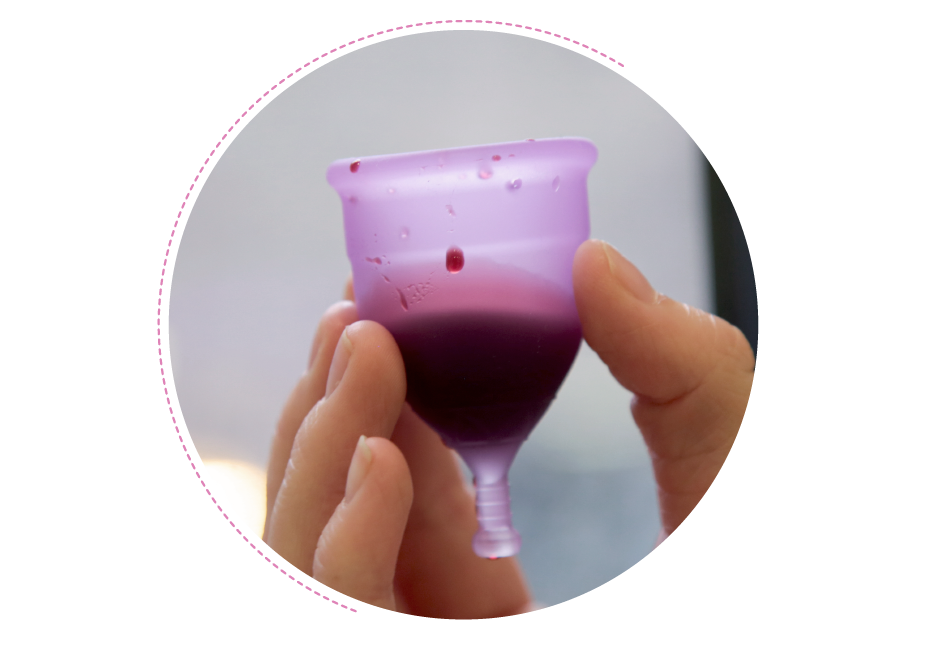 A hand holds a menstrual cup that is filled with blood